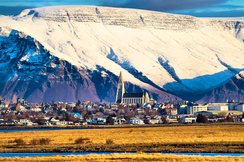 quali musei visitare a Reykjavik, veduta della città da lontano con sullo sfondo le montagne vulcaniche innevate e possenti